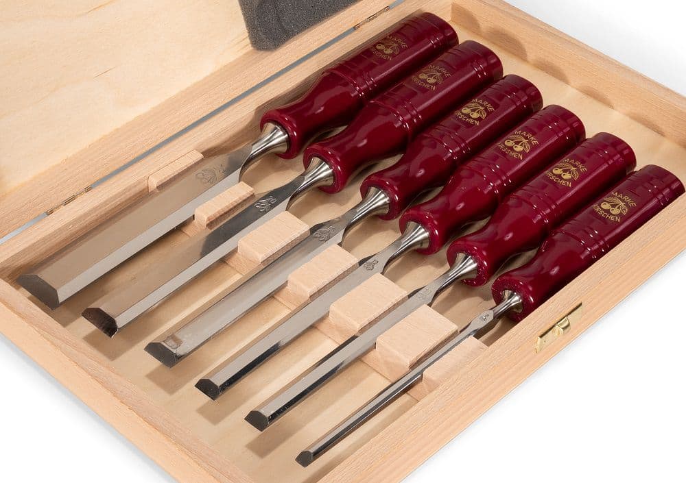 Set of red-handled chisels in a wooden case on a white background