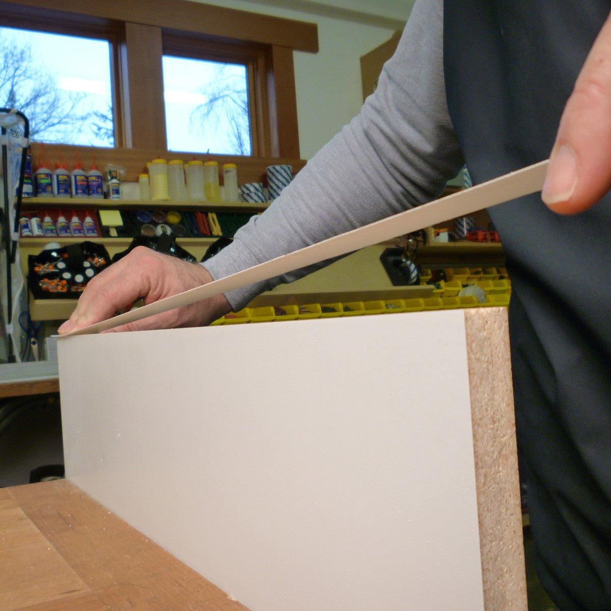 FastCap FastEdge PVC Peel and Stick White Edge Banding roll being applied to a cabinet edge