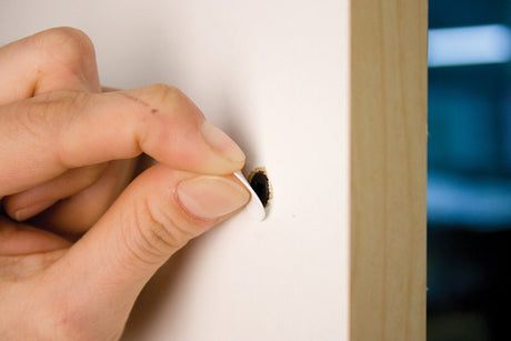 FastCap white PVC self-adhesive screw cover caps in a standard box of 1060 caps on a wooden surface