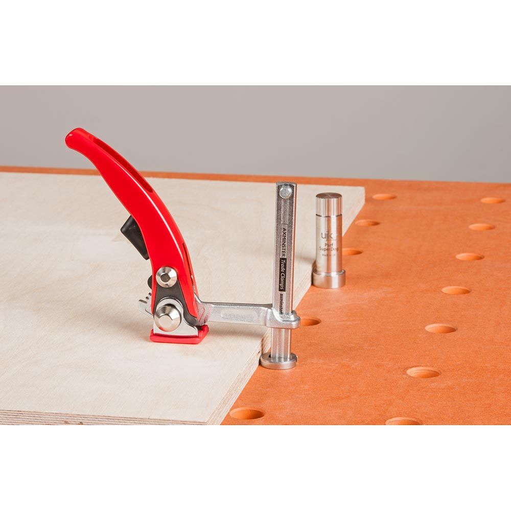 UJK Hold Down Ratchet Clamp, 60mm throat, 90mm clamping capacity in action on a workbench with dog holes