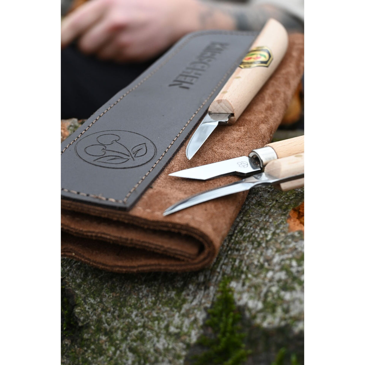 Three carving knives with wooden handles and brown suede case on a natural background