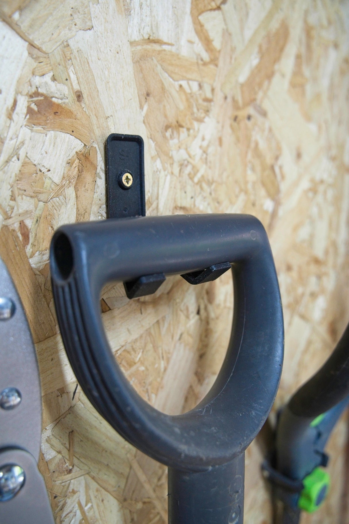 Black modular tool wall hooks from Superhooks Starter Bundle hanging on a wall in a workshop