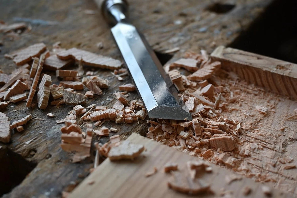 Wood chisel on a wooden surface with wood shavings