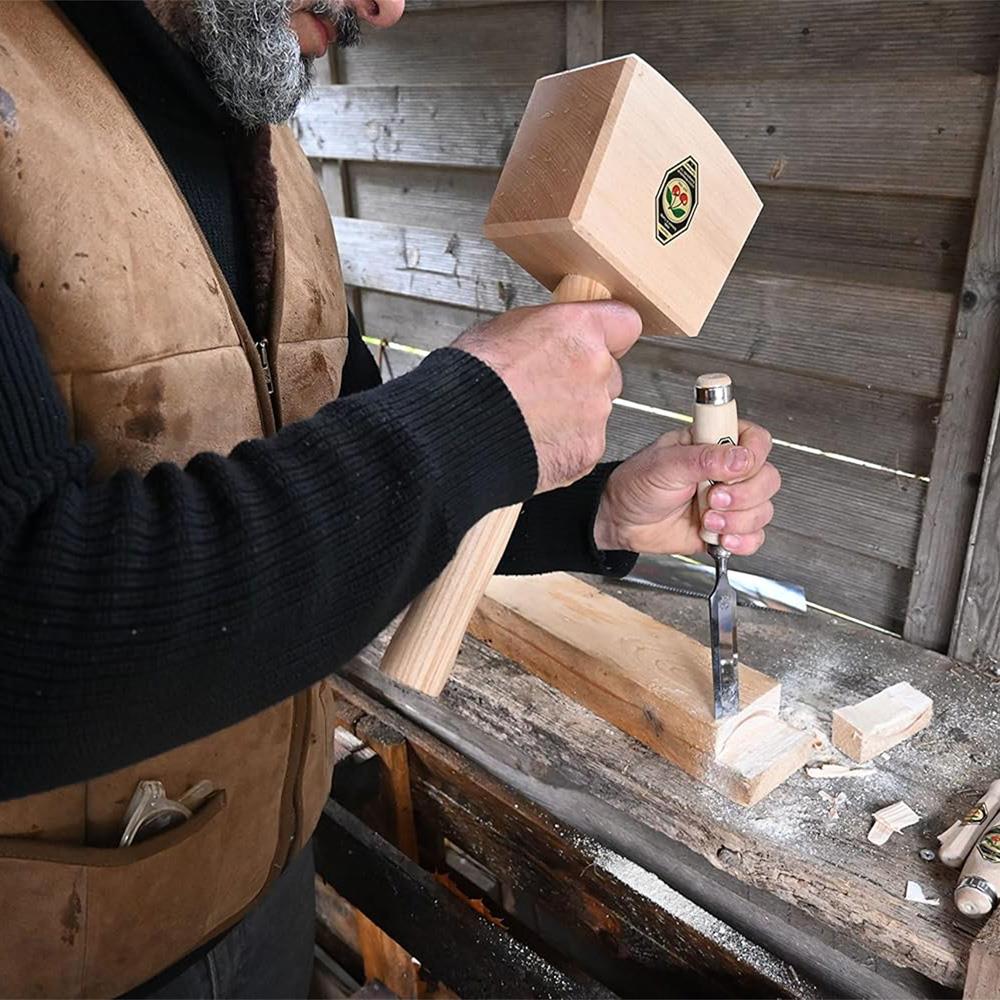 Person working with a wooden mallet and chisel on a wooden surface