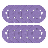 Multiple purple sanding discs with holes on a white background