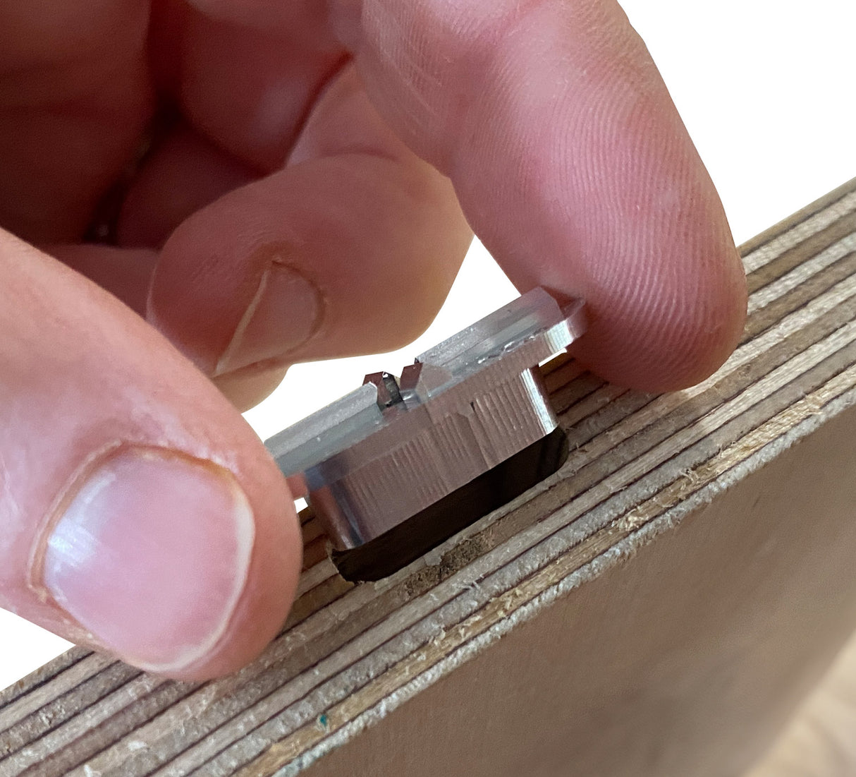 Close up of hands putting FastCap metal Mortise Marker into mortise in timber 