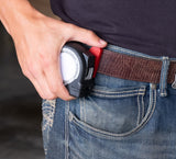 Hand securing tape measure into Fastcap's Tape measure lock on a belt with a blurred background