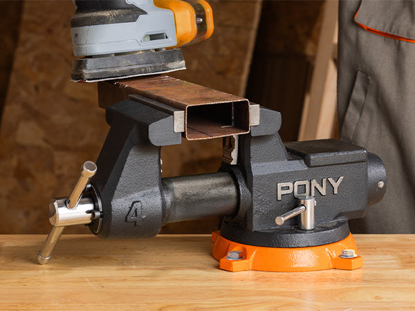 Pony vice holding a piece of metal on a wooden surface with a blurred background