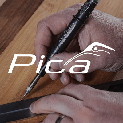 Person using a Pica pen on a wooden surface with the brand logo displayed.
